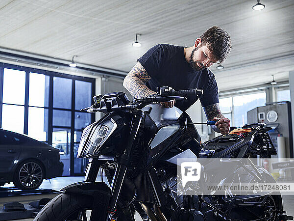 Young technician repairing motorcycle while working at workshop