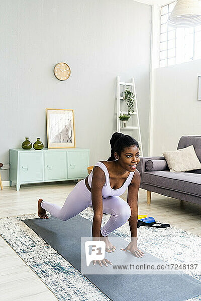 Active woman exercising on mat at home