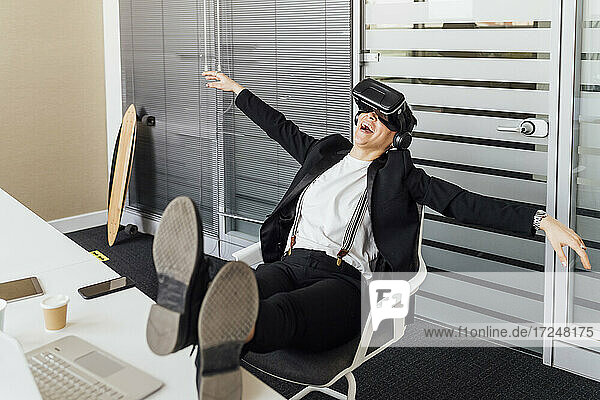 Fröhliche Geschäftsfrau mit Virtual-Reality-Headset genießt im Büro