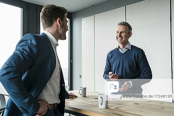 Smiling business people discussing at table in office cafe
