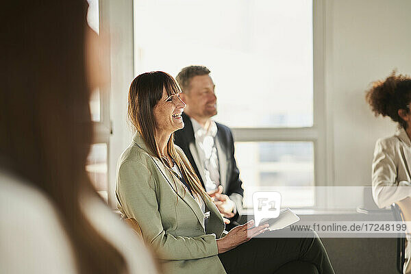 Lächelnde reife Geschäftsfrau  die eine Bildungsveranstaltung mit Kollegen im Büro besucht