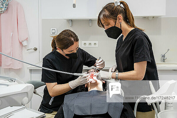 Zahnärztinnen reinigen die Zähne eines Patienten in einer medizinischen Klinik
