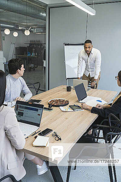 Geschäftsmann diskutiert mit männlichen und weiblichen Kollegen während einer Besprechung im Büro