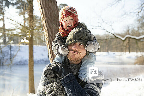 Father carrying son on shoulder during winter