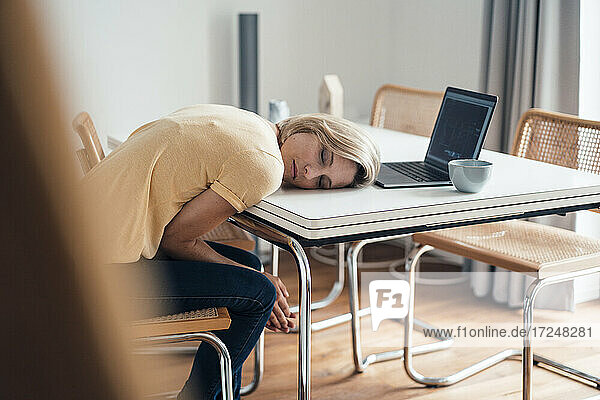 Müde weibliche Berufstätige schlafen auf dem Tisch zu Hause
