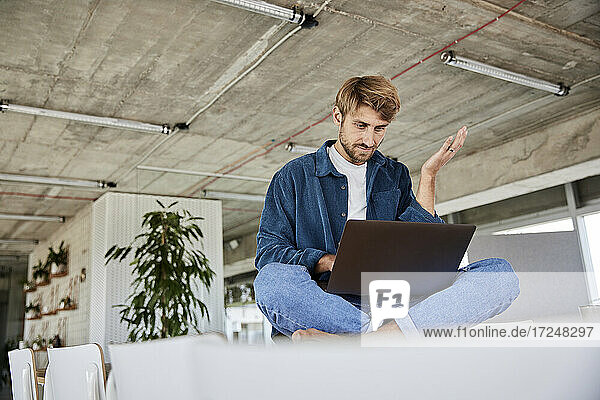 Mann gestikuliert bei der Benutzung eines Laptops im Loft