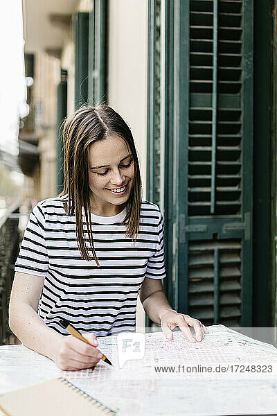 Lächelnde Touristin beim Zeichnen auf Papier auf dem Balkon