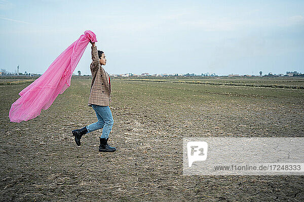 Frau läuft mit rosa Tüllnetz auf Feld