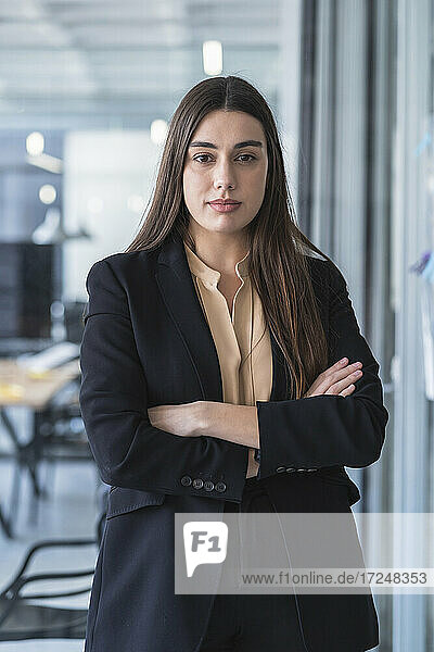Businesswoman with arms crossed staring while standing in coworking office