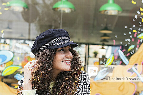 Brown curly hair woman looking away at sidewalk cafe