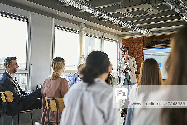 Female entrepreneur giving presentation to colleagues in educational event at office