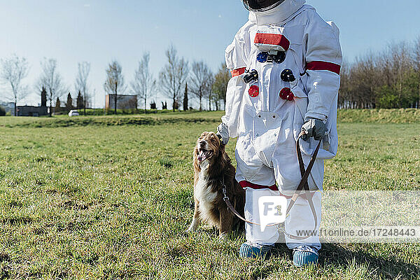 Astronaut stehend mit Haustier im Gras an einem sonnigen Tag