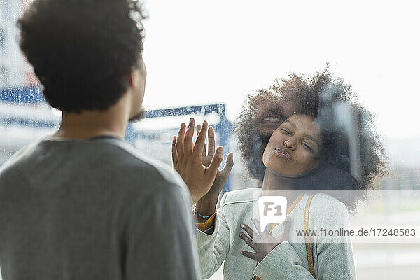 Afro-Frau  die einen männlichen Freund durch eine Glaswand anschmachtet