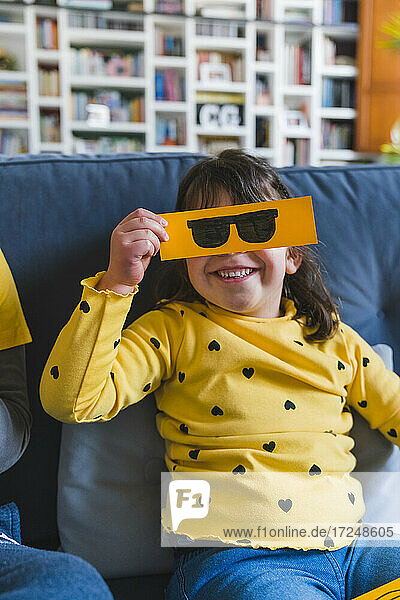Mädchen hält Sonnenbrille Emoticon beim Spielen zu Hause