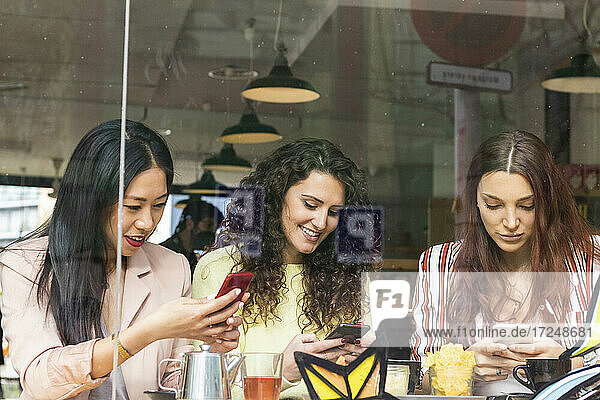 Young women using mobile phones at cafe
