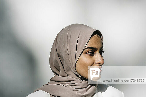 Beautiful smiling woman wearing hijab in front of white wall
