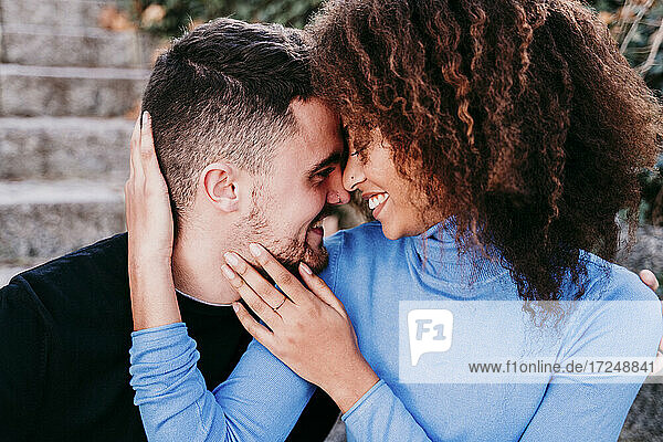 Curly hair girlfriend smiling with arm around on boyfriend