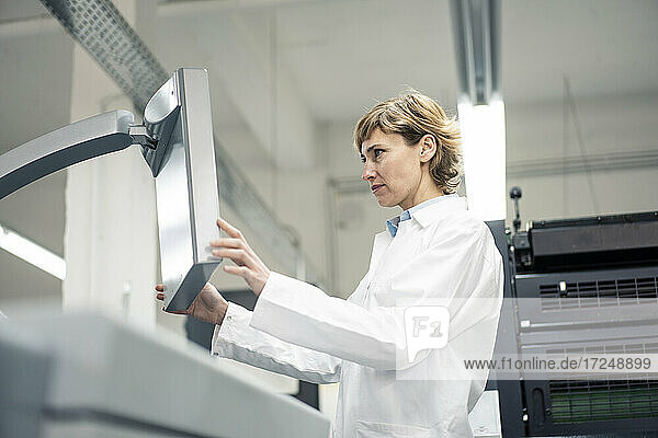 Reife Wissenschaftlerin bei der Bedienung einer Druckmaschine im Labor