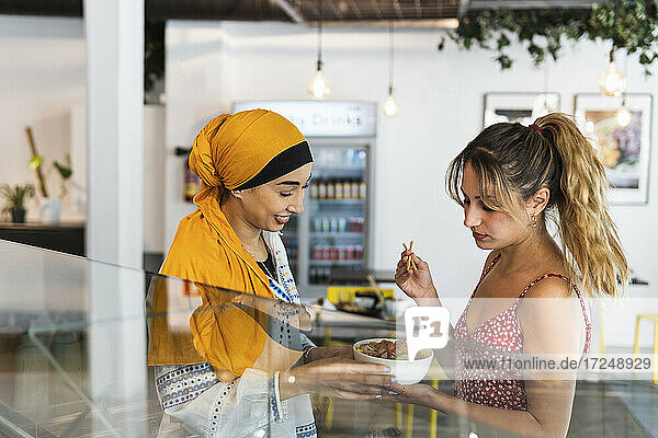 Multiethnische Frauen teilen sich im Restaurant eine Poke-Schüssel