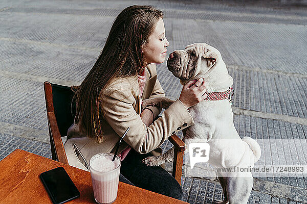 Frau betrachtet ihr Haustier  während sie in einem Straßencafé sitzt