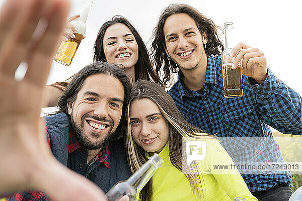 Glückliche Freunde zeigen Bierflaschen vor dem Himmel