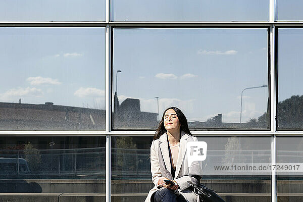 Unternehmerin sitzt mit geschlossenen Augen an einem sonnigen Tag