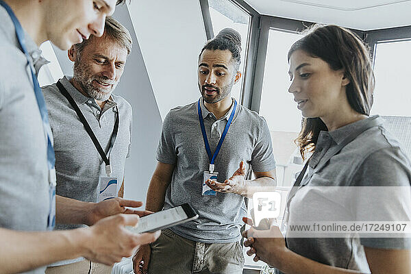 Männlicher Fachmann  der während einer Konferenz über ein digitales Tablet mit Kollegen diskutiert