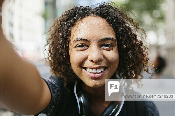 Woman with curly hair taking selfie in city