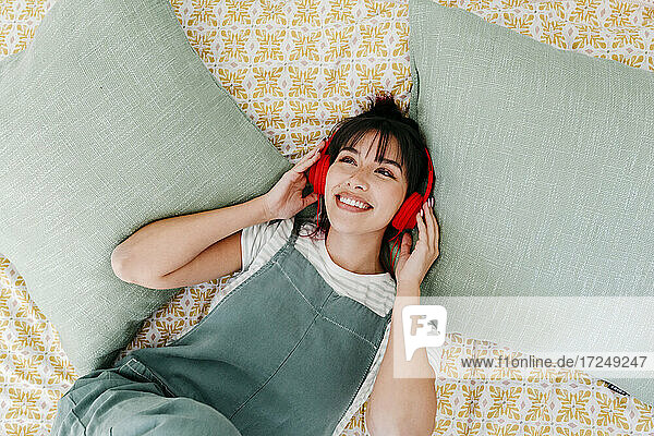 Woman with headphones listening music while day dreaming at home