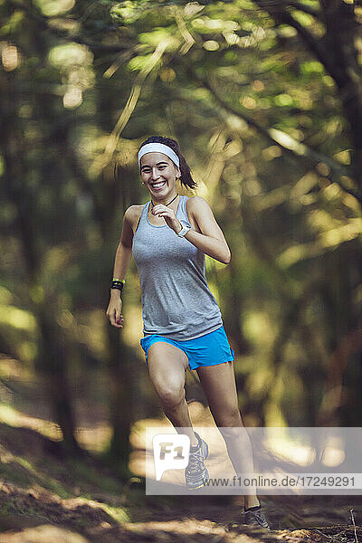 Lächelnde junge Sportlerin beim Laufen im Wald