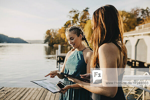 Female planners discussing over clipboard near lake