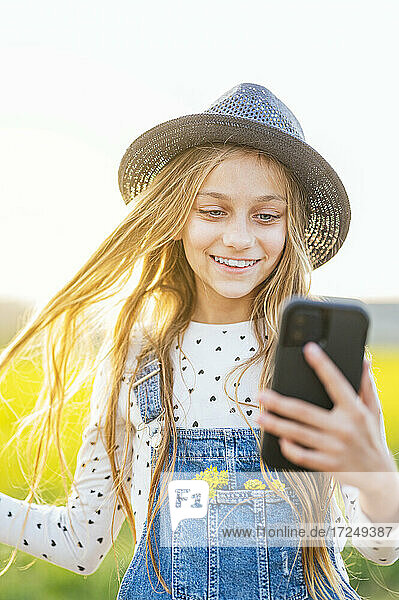 Happy girl taking selfie through smart phone at agricultural field