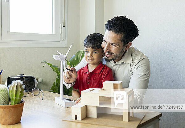 Lächelnder männlicher Architekt zeigt seinem Sohn im Büro zu Hause ein Turbinenmodell