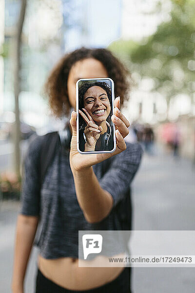 Frau zeigt Selfie auf Smartphone in der Stadt