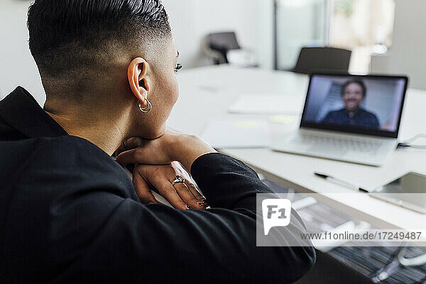 Geschäftsfrau diskutiert mit einem männlichen Kollegen per Videoanruf am Laptop im Büro