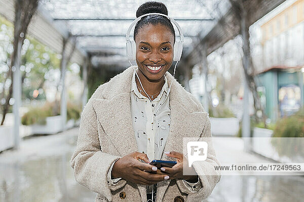 Happy beautiful woman with headphones holding mobile phone