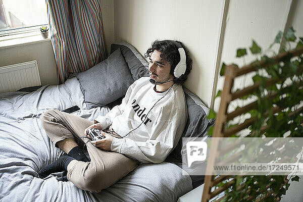 Young man with headphones playing video game at home