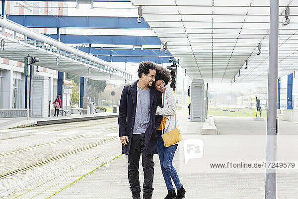 Cheerful couple embracing at railroad station