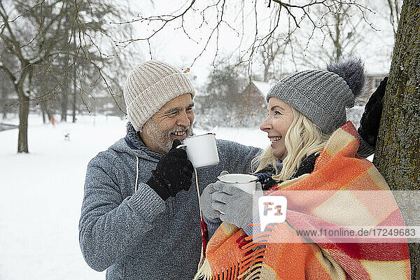 Smiling senior couple drinking tea in mug during winter