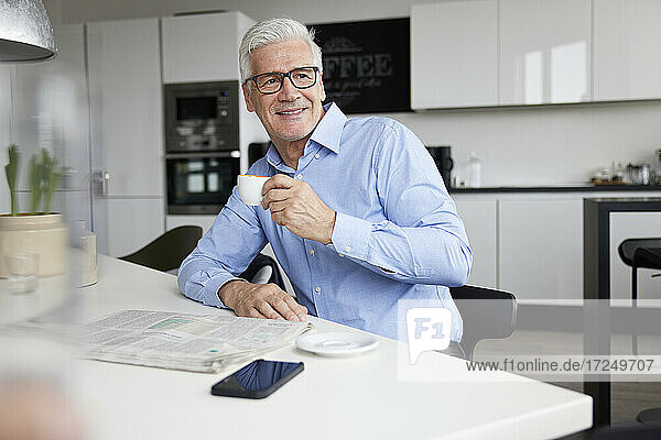 Smiling mature entrepreneur with coffee cup at cafeteria