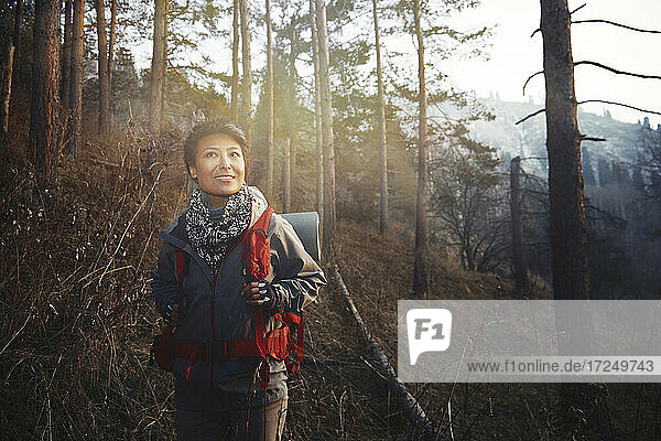 Mittlere erwachsene Frau lächelt beim Wandern im Wald