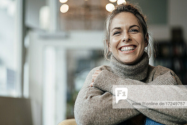 Mid adult woman wearing sweater smiling at cafe