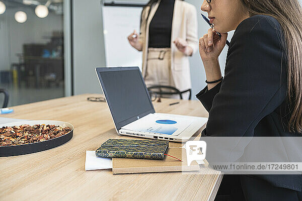 Geschäftsfrau beim Analysieren von Finanzdaten über Laptop im Büro