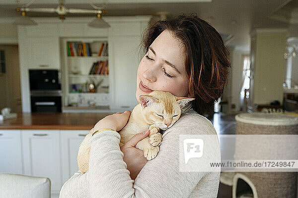 Schöne Frau umarmt Katze zu Hause