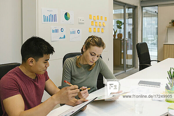 Männliche und weibliche Fachkräfte arbeiten an Finanzberichten am Schreibtisch in einem Coworking-Büro