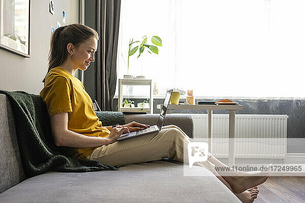 Woman using laptop while sitting on sofa