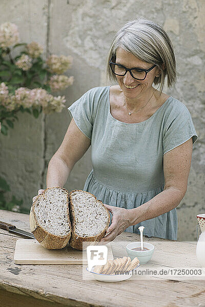 Lächelnde Frau mit halbiertem Brot am Tisch