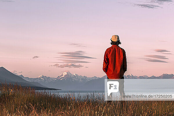 Neuseeland  Canterbury  Rückansicht eines jungen Mannes mit Blick auf den Lake Pukaki bei Sonnenuntergang