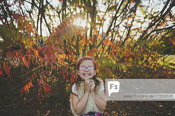 Smiling girl wearing eyeglasses in front of plants during autumn