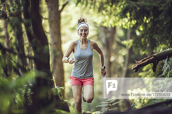 Excited young sportswoman running in forest